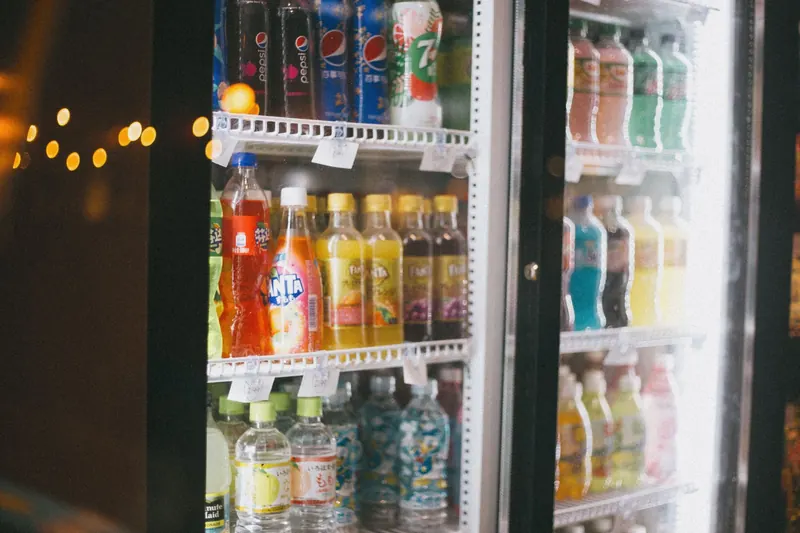 Assorted bottles of soft drinks in a commercial refrigerator with glass doors